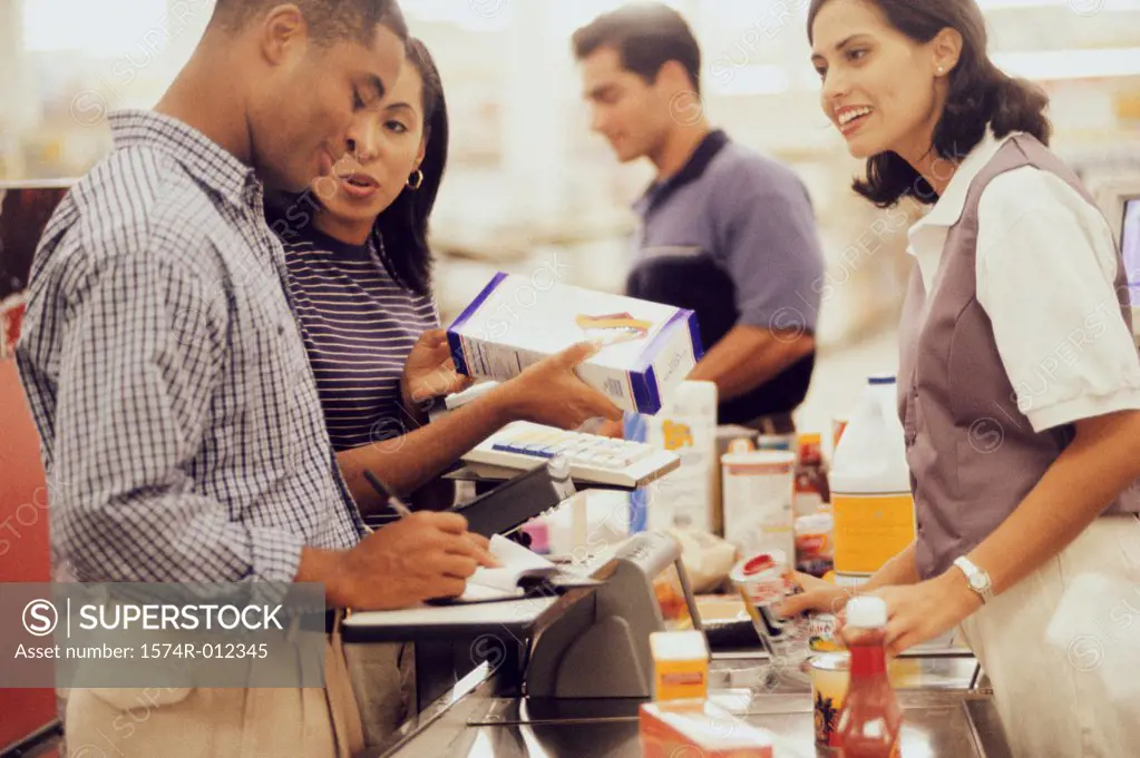 Side profile of a mid adult couple at a checkout counter in a supermarket