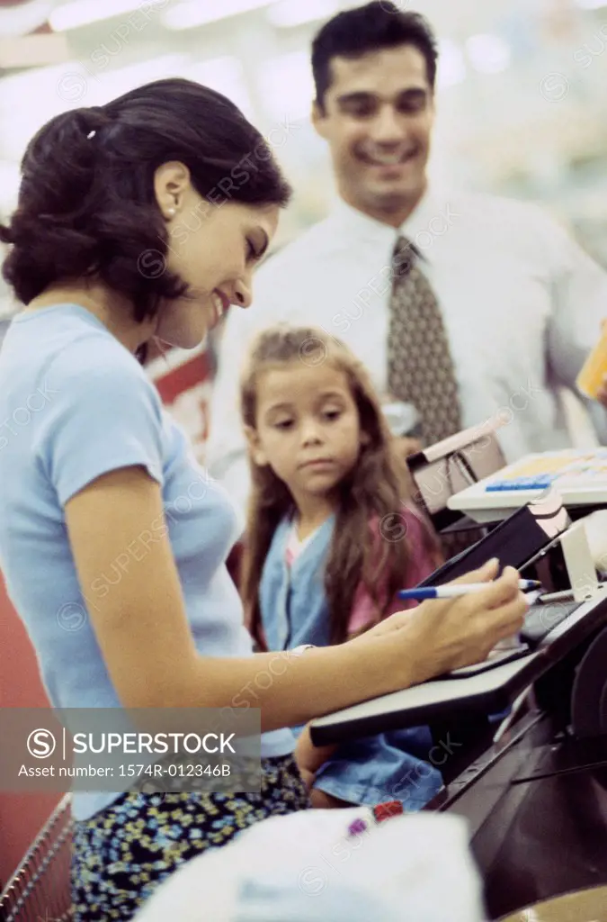 Side profile of a young woman with her daughter standing at a checkout counter in a supermarket