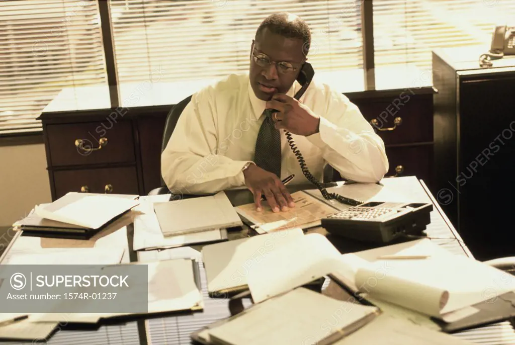 Businessman talking on the landline telephone on the desk