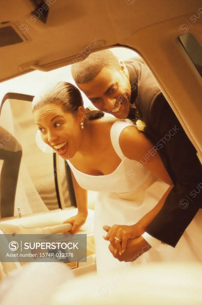 Newlywed couple looking inside of a car