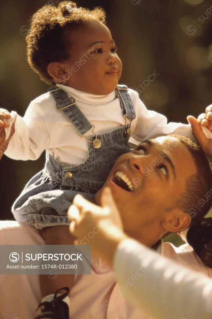 Close-up of a father carrying his daughter on his shoulders