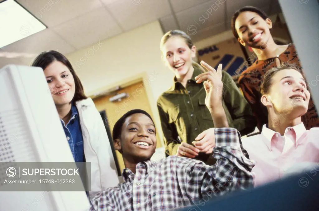Low angle view of high school students in front of a computer in a classroom
