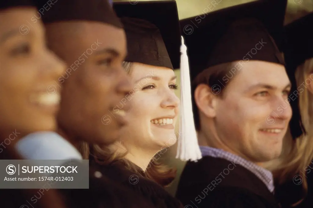 Side profile of four young graduates smiling