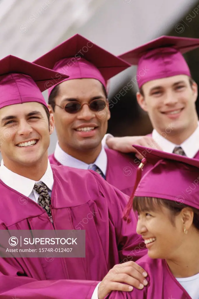 Four young graduates smiling