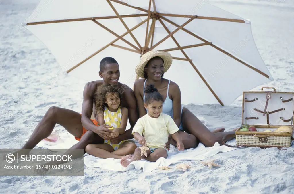 Parents with their two daughters sitting on the beach