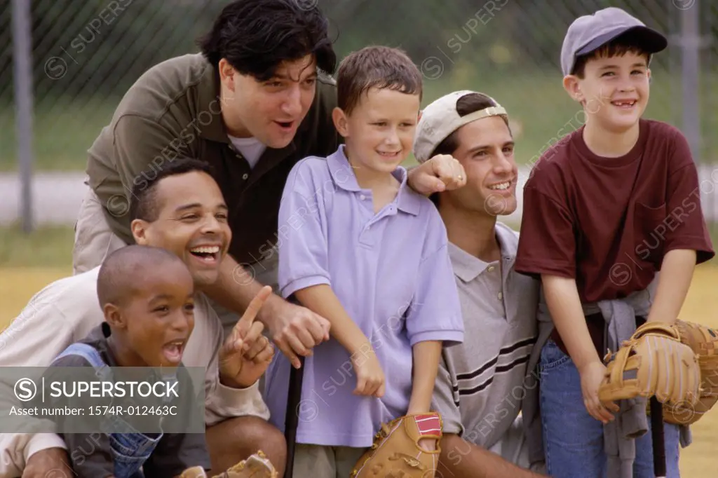 Close-up of three fathers with their sons wearing baseball gloves in a baseball field