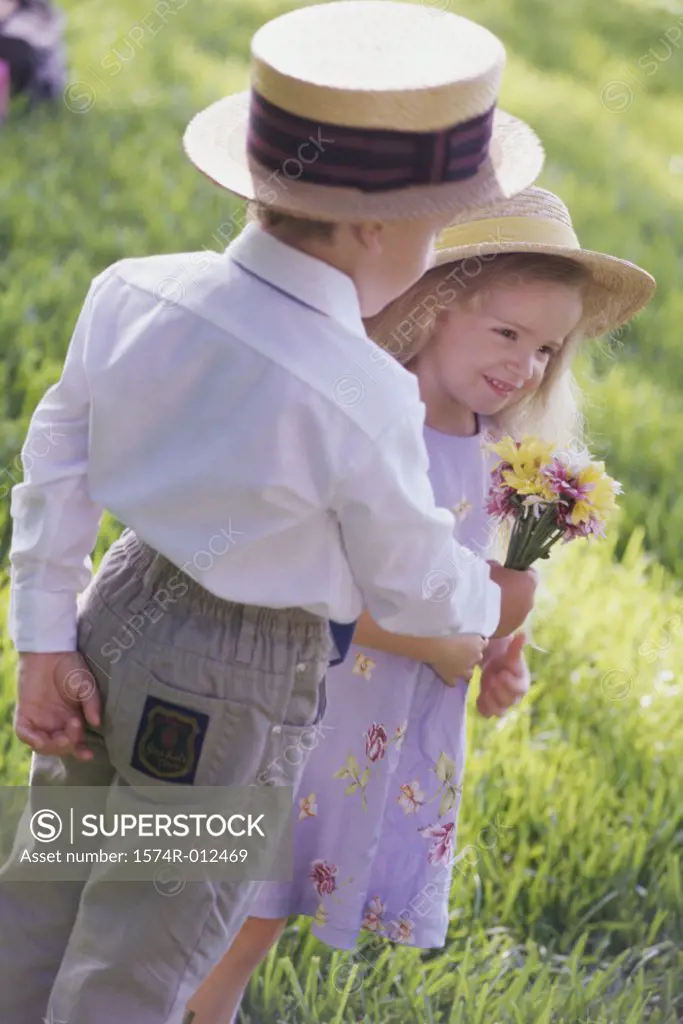 Rear view of a boy giving a bouquet of flowers to a girl