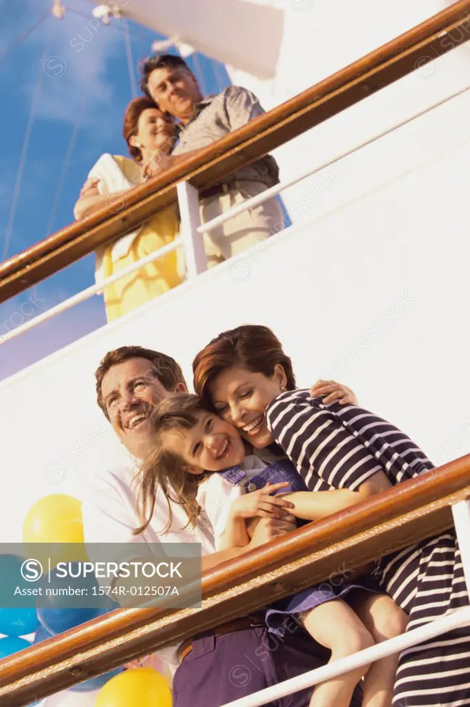 Low angle view of a mid adult couple with their daughter standing on the deck of a cruise ship laughing