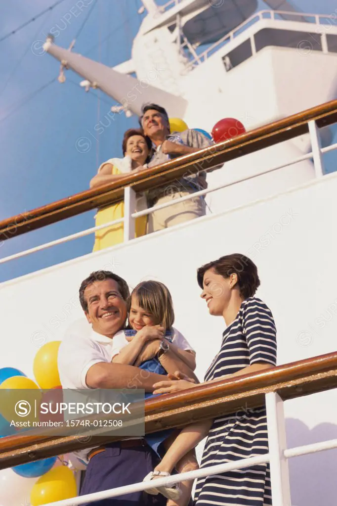 Low angle view of a mid adult couple with their daughter standing on the deck of a cruise ship smiling