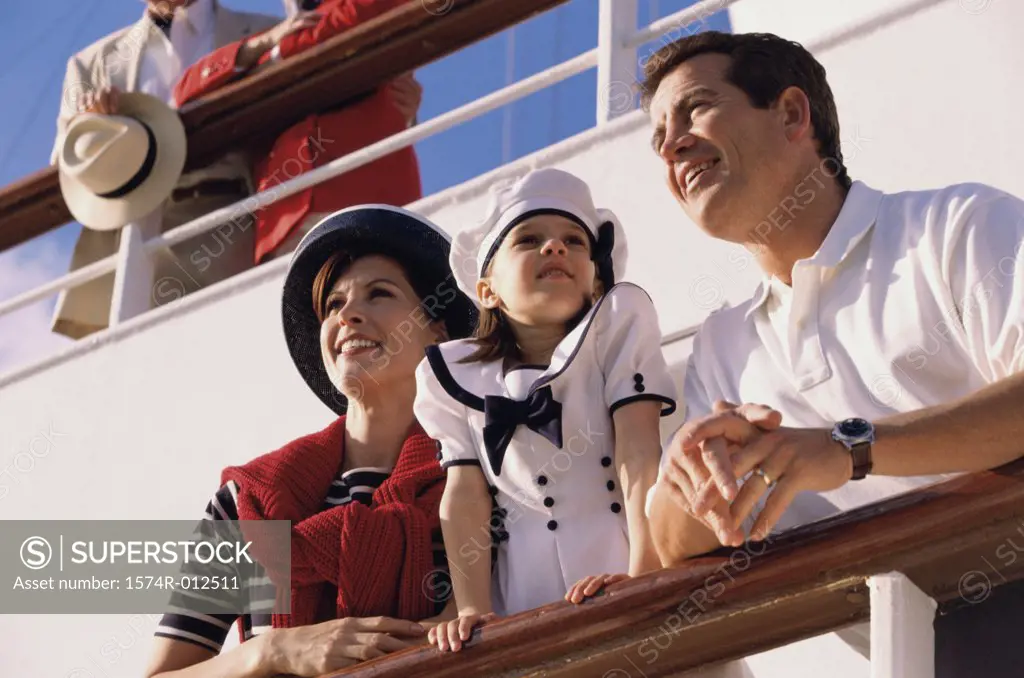 Low angle view of a mid adult couple with their daughter standing on the deck of a cruise ship