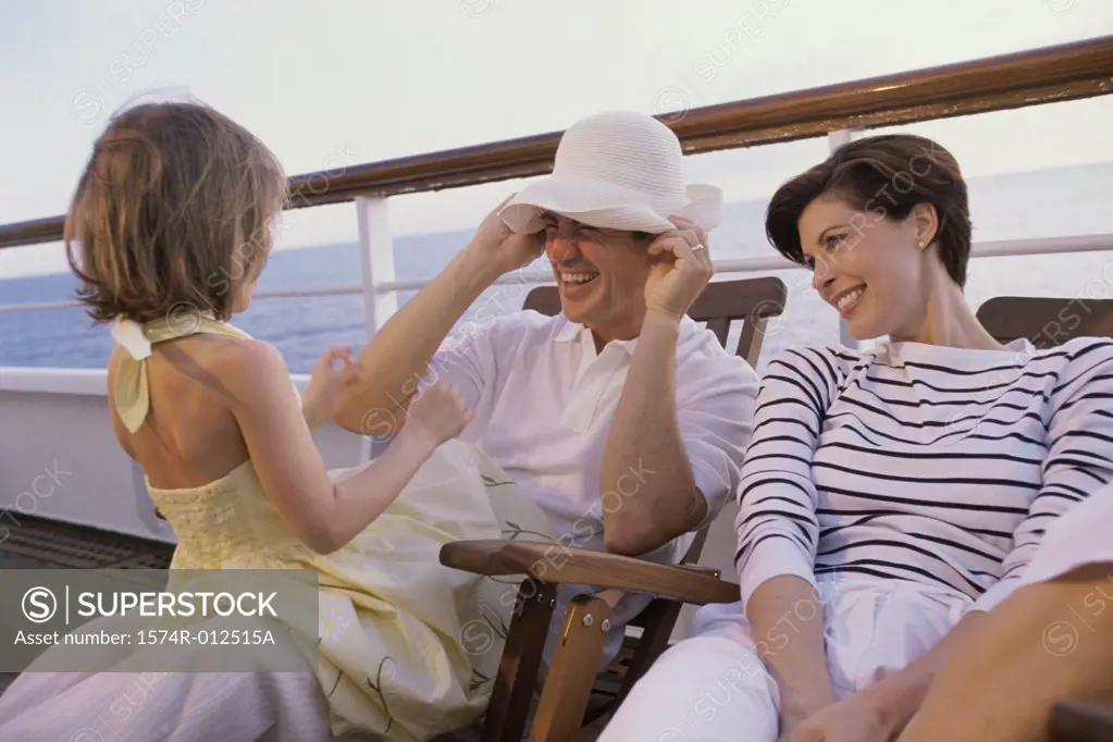 Close-up of parents sitting with their daughter on the deck of a cruise ship