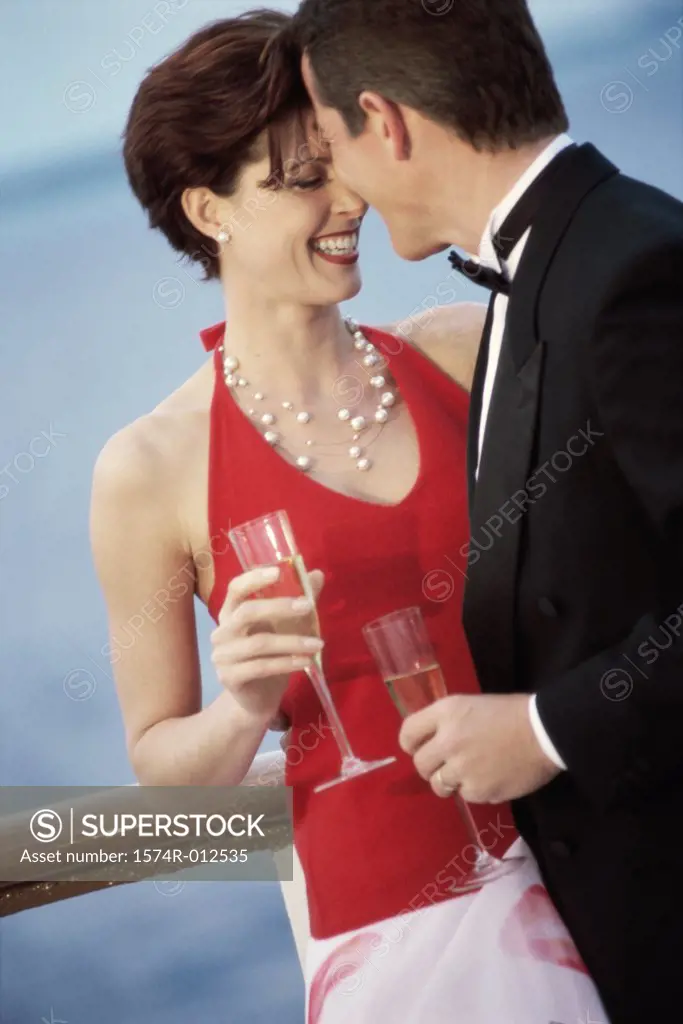 Close-up of a young couple holding champagne flutes on the deck of a cruise ship
