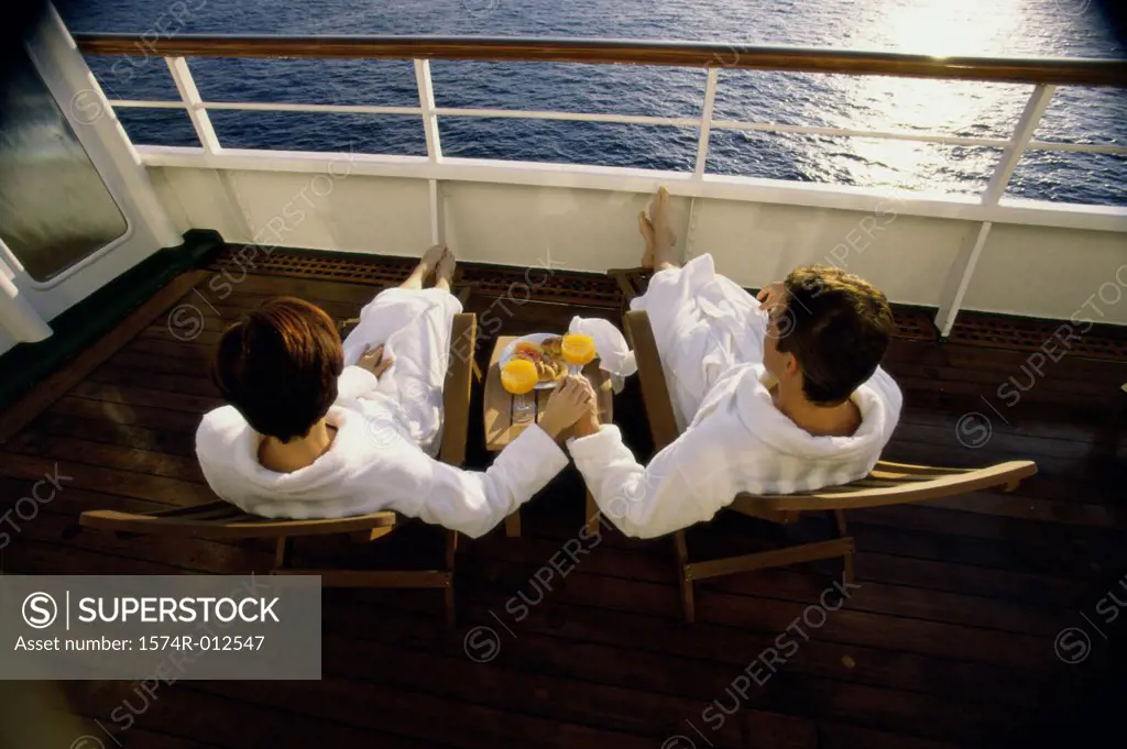 High angle view of a mid adult couple sitting in deck chairs on a cruise ship