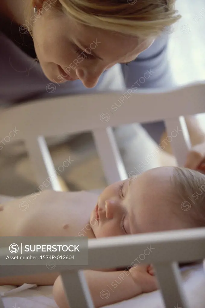 Close-up of a mother looking at her son sleeping in a crib