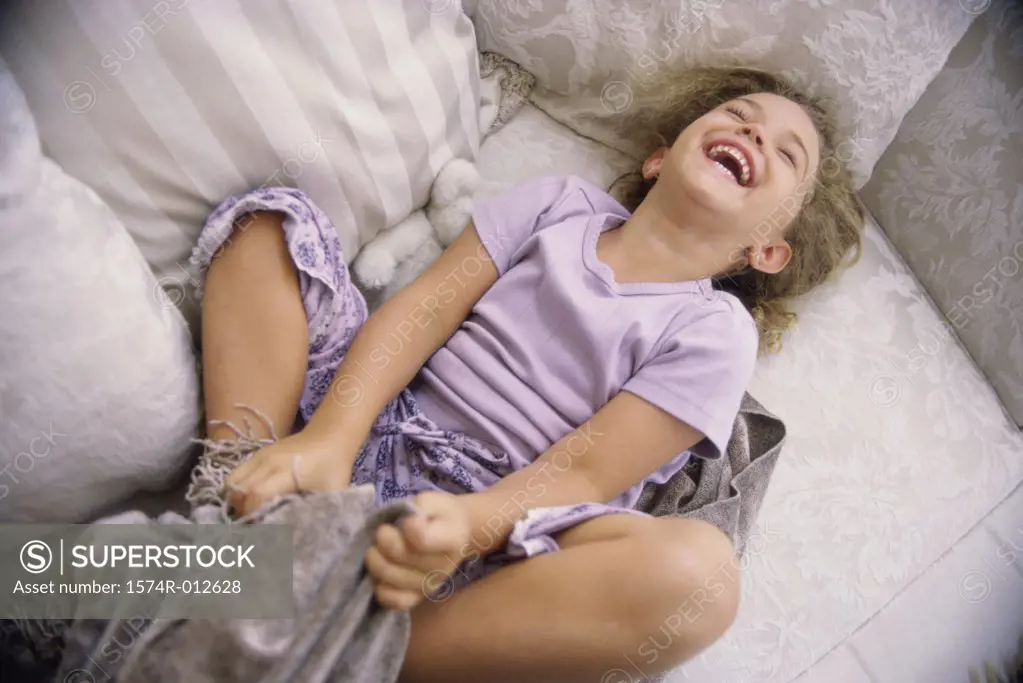 High angle view of a girl lying down on a couch laughing