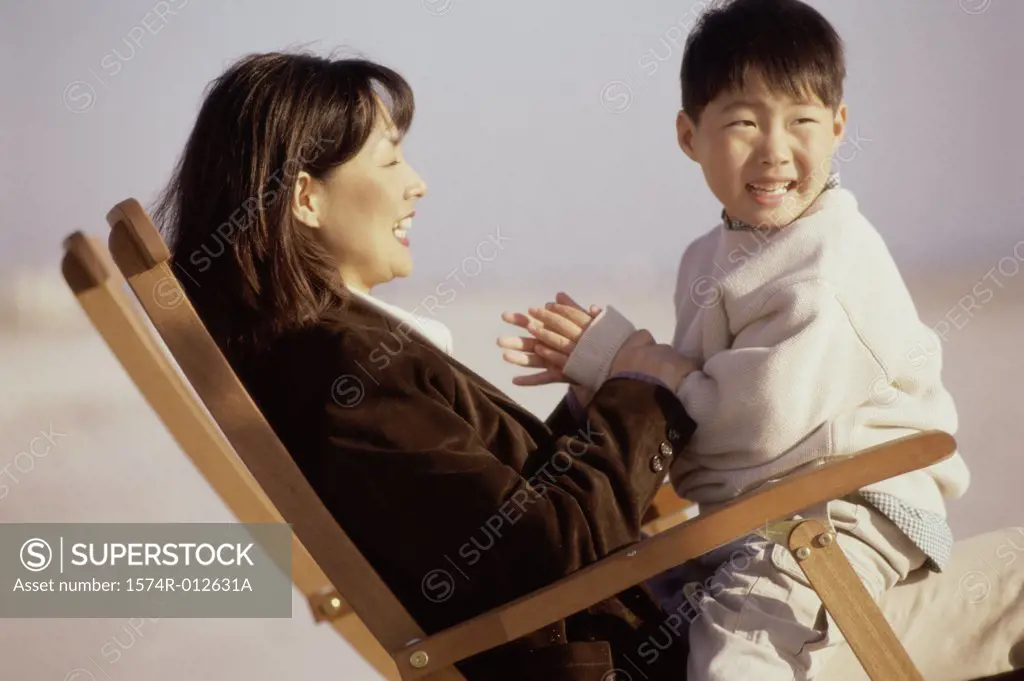 Side profile of a mother and son sitting in a beach chair
