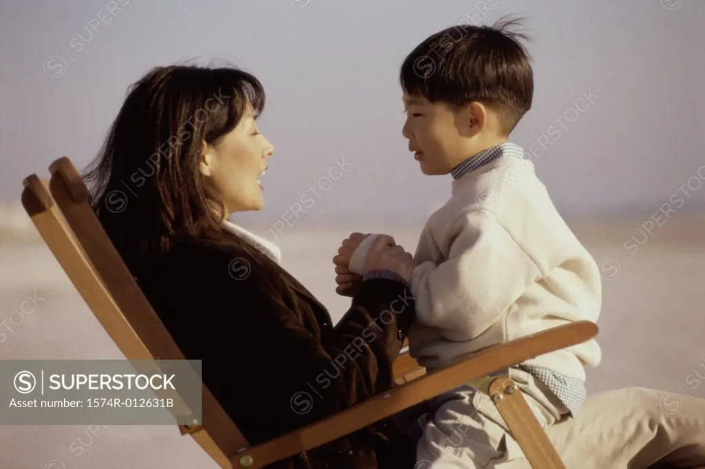 Side profile of a mother and son sitting in an beach chair