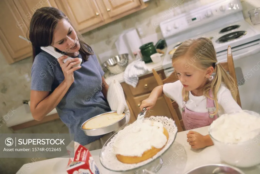 Daughter helping her mother bake a cake