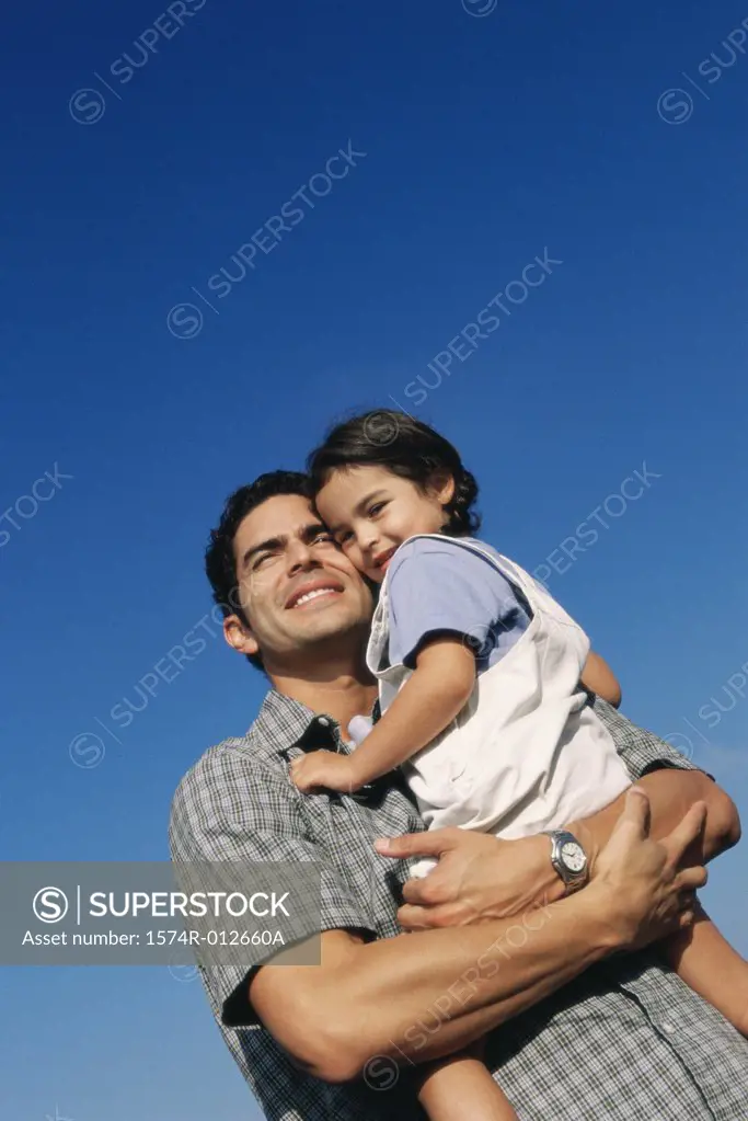 Low angle view of a father carrying his daughter