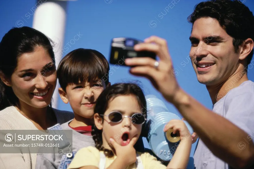Mid adult man taking a photograph of his family