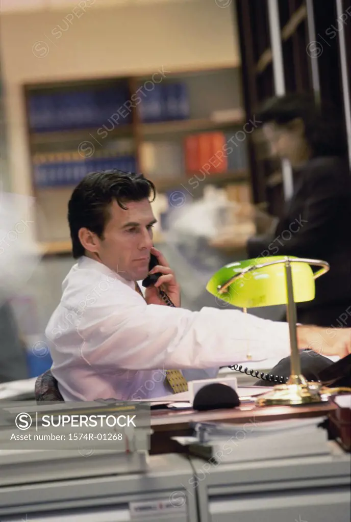 Young businessman using the landline telephone at his desk