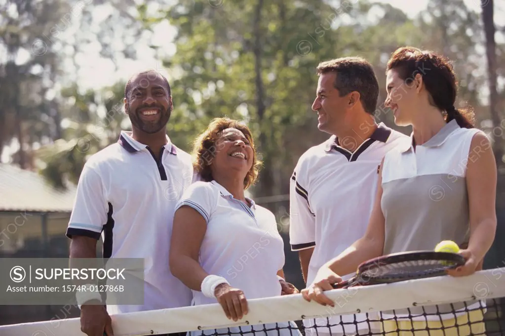 Low angle view of two mid adult couples smiling on a tennis court