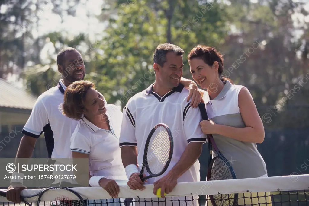 Two mid adult couples playing tennis