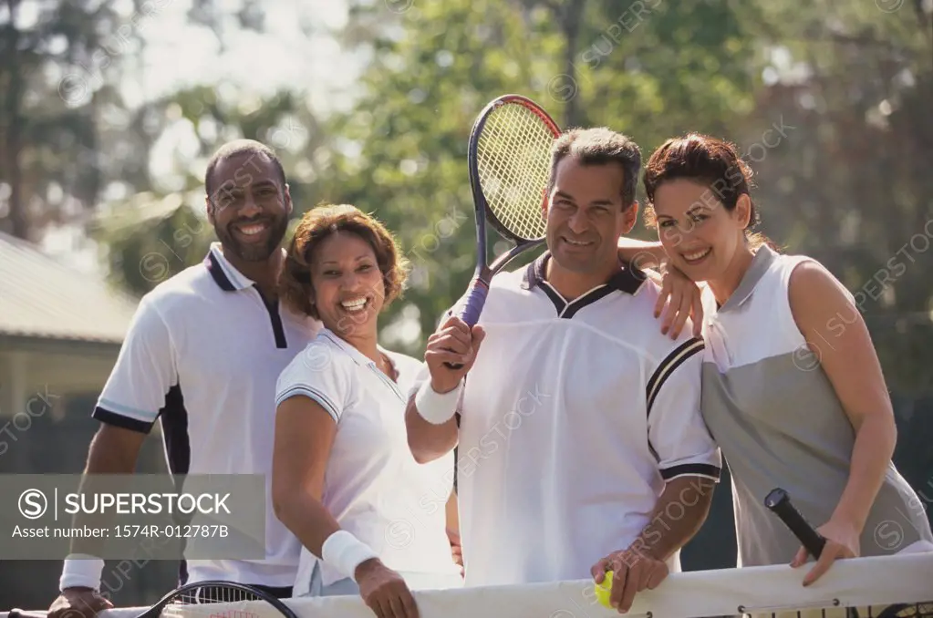 Portrait of two mid adult couples smiling on a tennis court