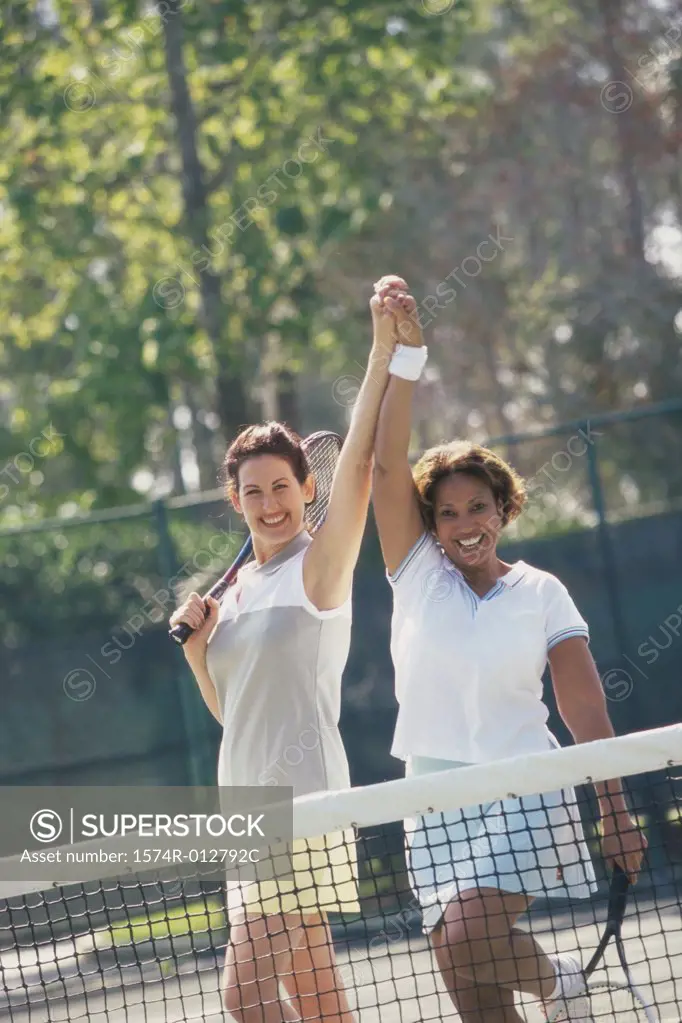 Portrait of two mid adult women cheering after winning a tennis match
