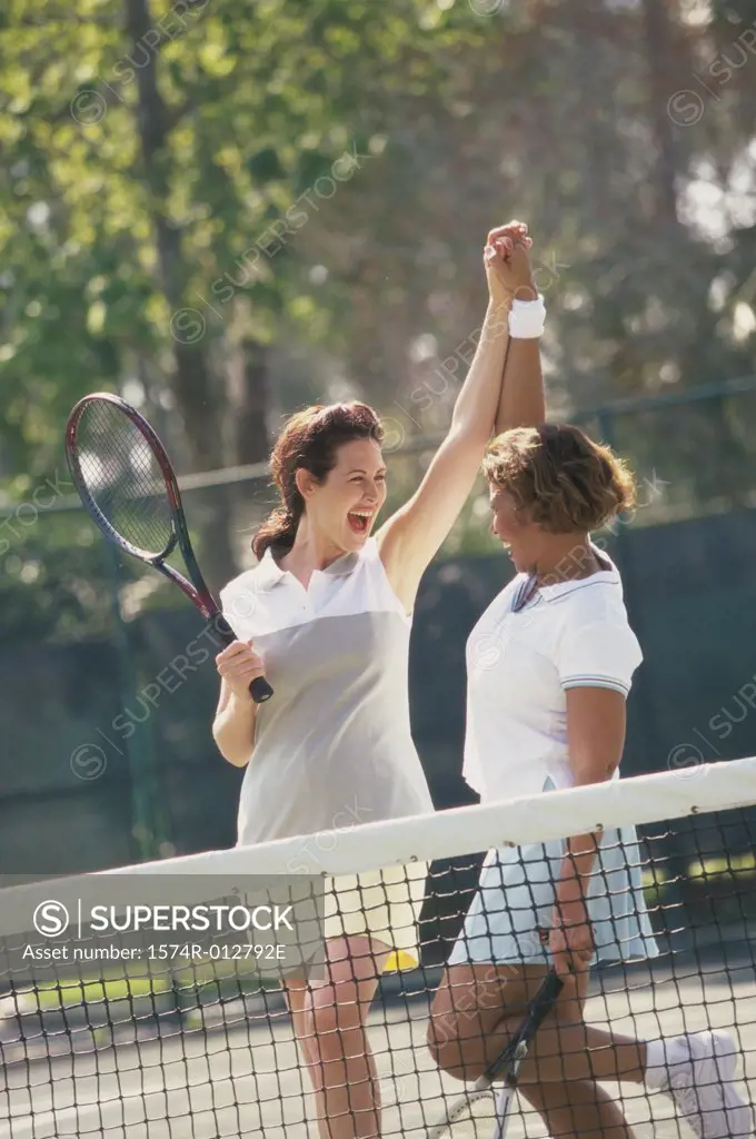 Two mid adult women cheering after winning a tennis match