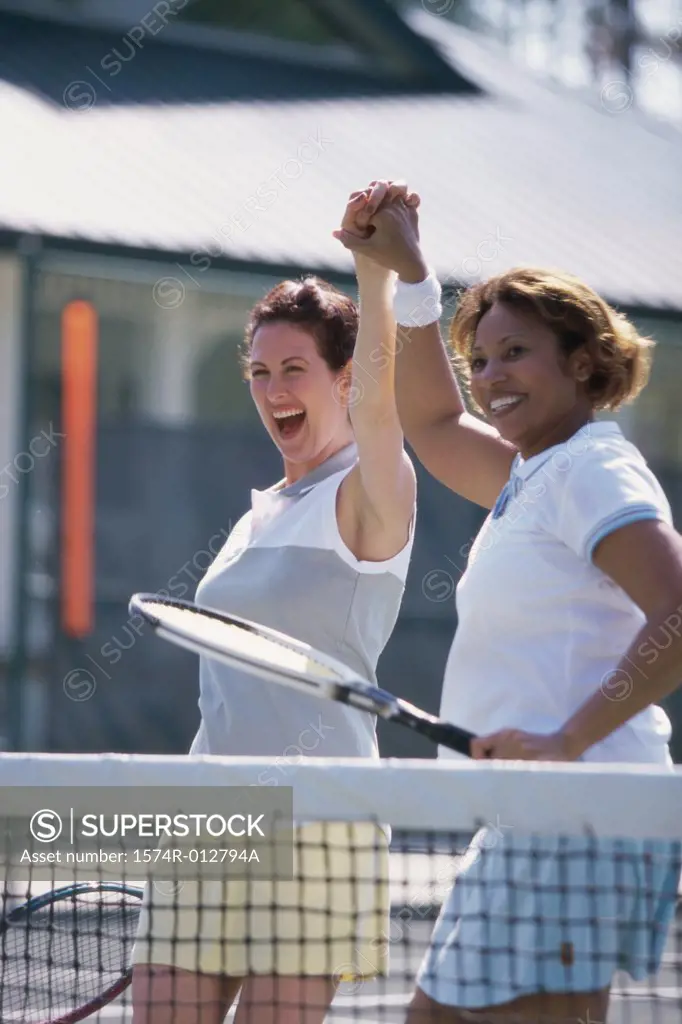 Two mid adult women cheering after winning a match