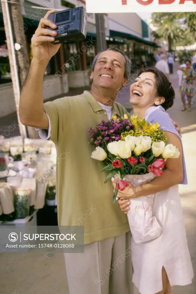 Mature couple taking a photograph of themselves in a market