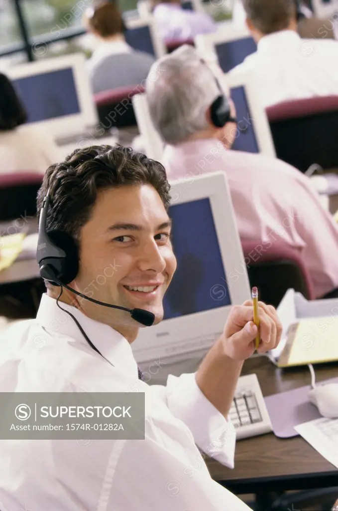 Portrait of a male customer service representative sitting in front of a computer monitor