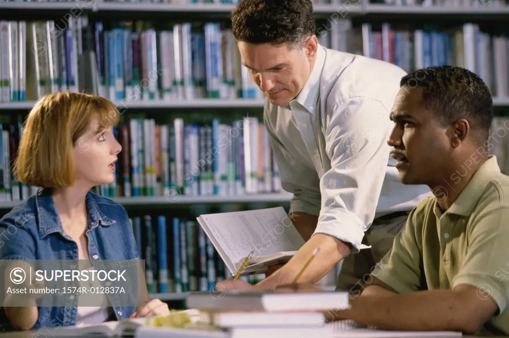 Young woman and two mid adult men studying in a library