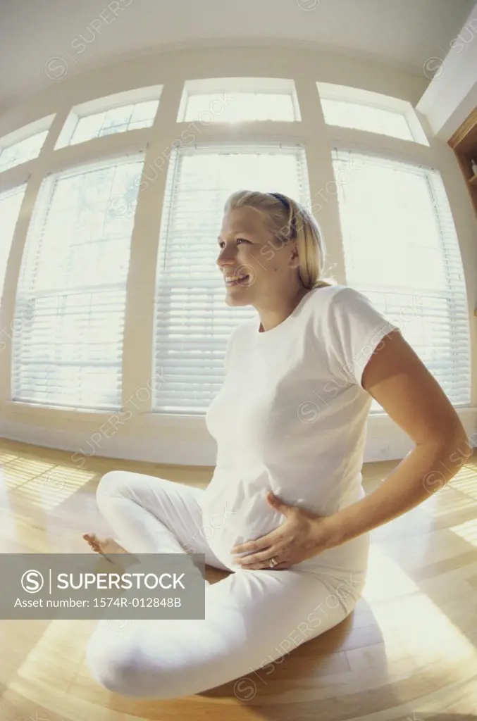 Side profile of a young pregnant woman sitting on the floor