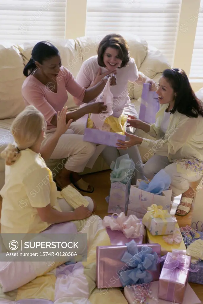 High angle view of four young women unwrapping gifts at a baby shower