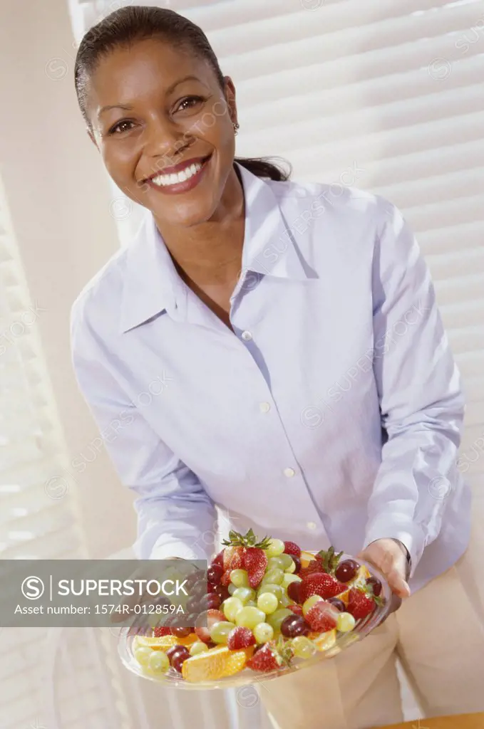 Portrait of a young woman holding a tray of mixed fruit