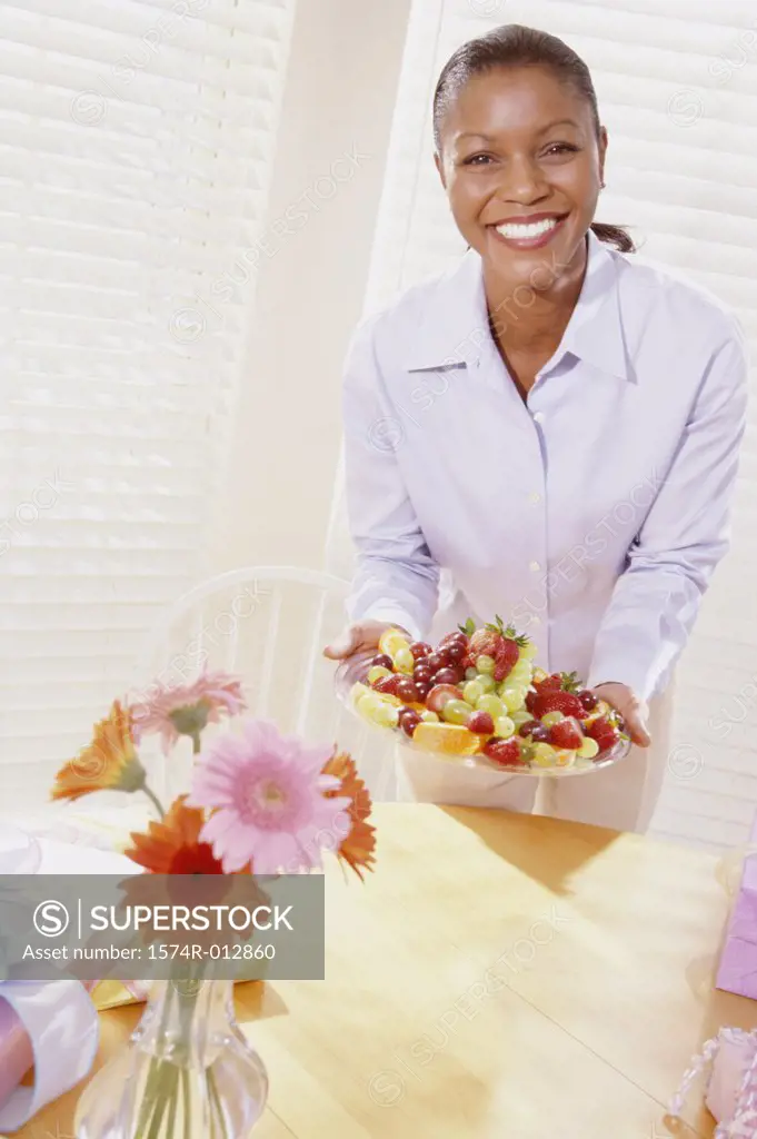 Portrait of a young woman holding a tray of mixed fruit