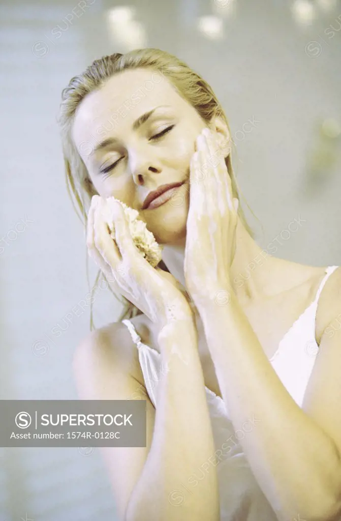 Young woman cleaning her face with a sponge