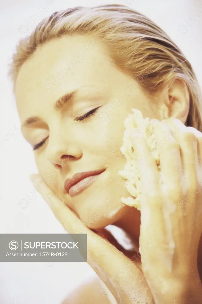 Close-up of a young woman cleaning her face with a sponge