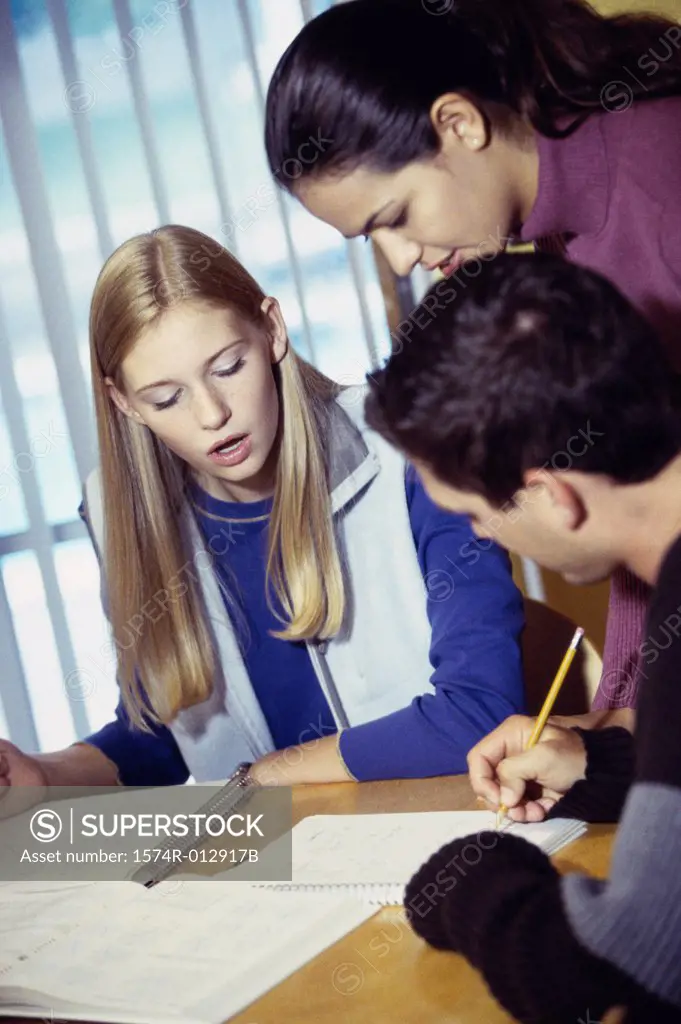 Two teenage girls with a teenage boy studying