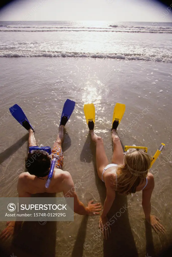 High angle view of a young couple wearing flippers relaxing on the beach