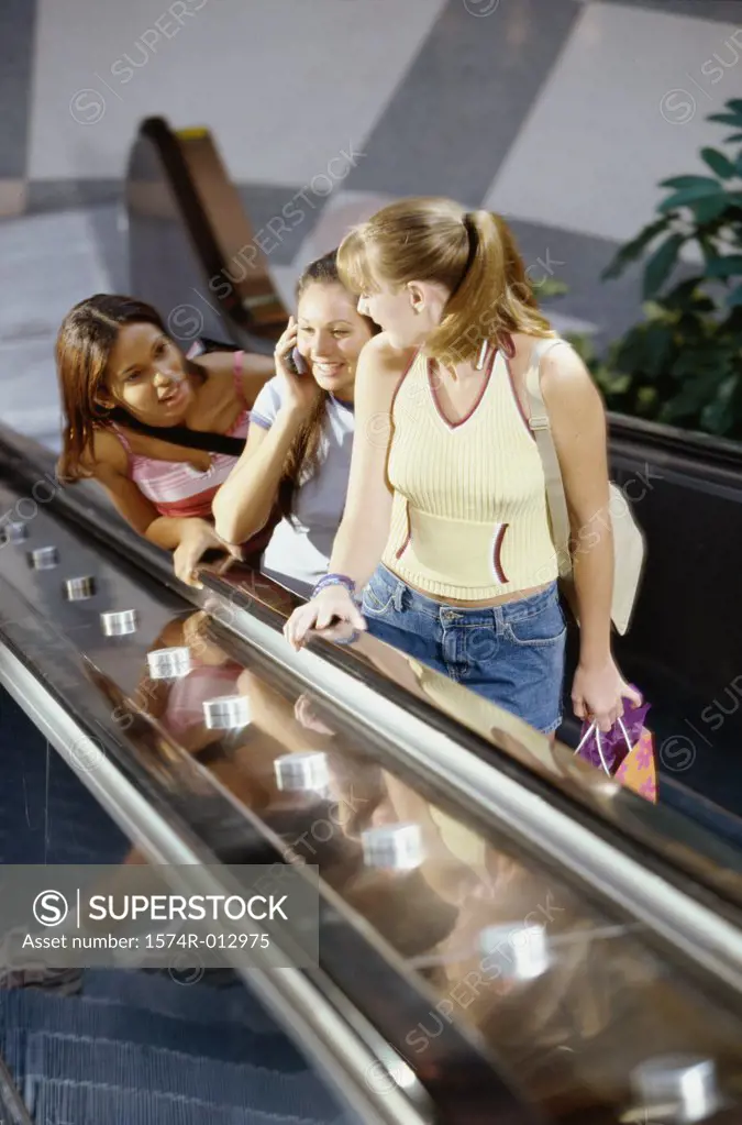 High angle view of three teenage girls standing on an escalator