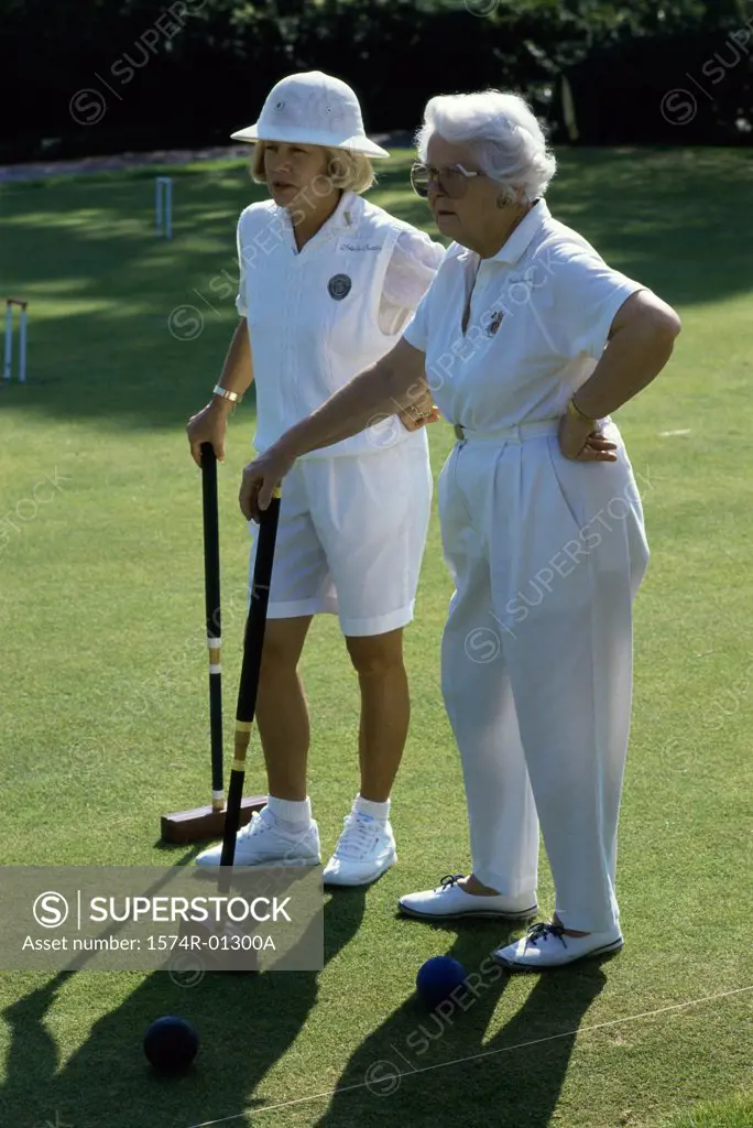 Two senior women standing on a golf course holding golf clubs