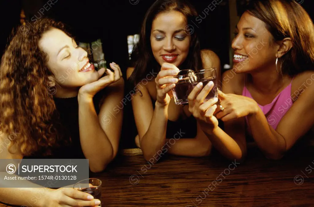 Three young women toasting with glasses in a bar