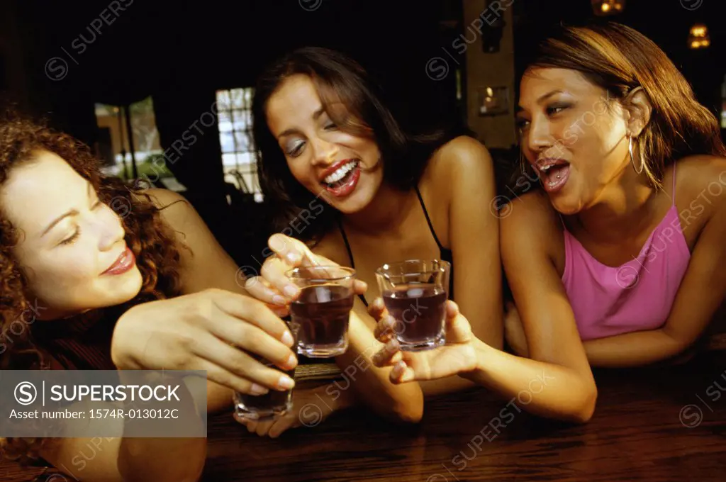 Three young women toasting with glasses in a bar