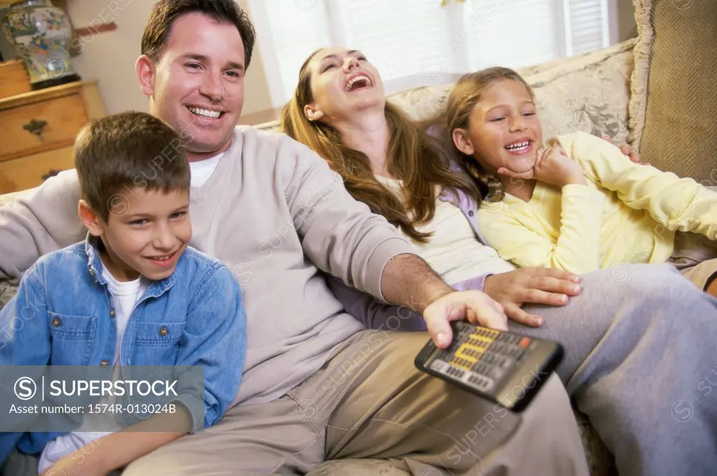 Parents watching television with their son and daughter