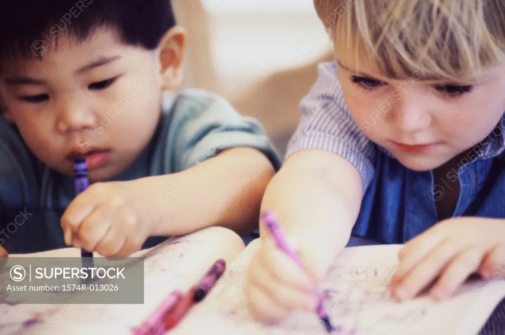 Close-up of two boys drawing with crayons