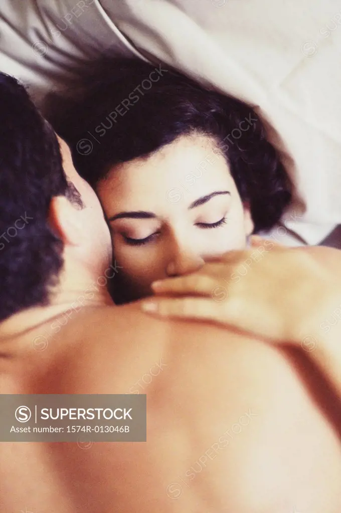 High angle view of a young couple lying on a bed and kissing