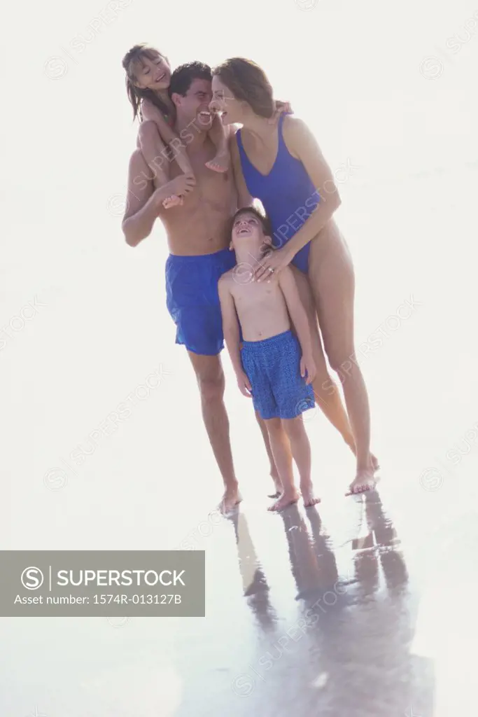 Parents standing with their two children on the beach